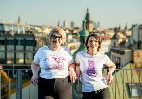 Sára a Kamila z Personky PRO smějící se v tričkách s potiskem jejich charitativního projektu pomáhajícího kočkám, portrétní fotografie v hezkých venkovních prostorech.